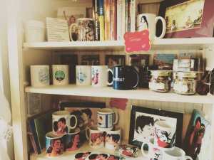 books shelf with queer feminist mugs, prints, books