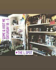 image of Instagram post with shop merchandise bookshelves with mugs, books, independent queer art, etc string lights around edges and words come and visit me Saturday 10-5, fresh merch